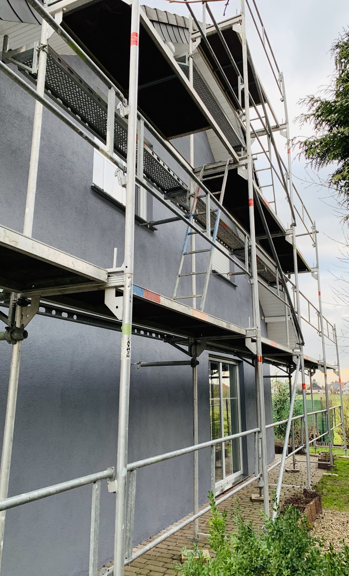 Fassadengerüst mit mehreren Ebenen an einem modernen Wohnhaus mit dunkler Fassade