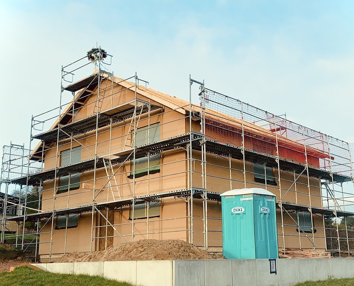 Gesamtansicht des Fassaden- und Dachfanggerüsts an einem Neubau mit Richtkranz