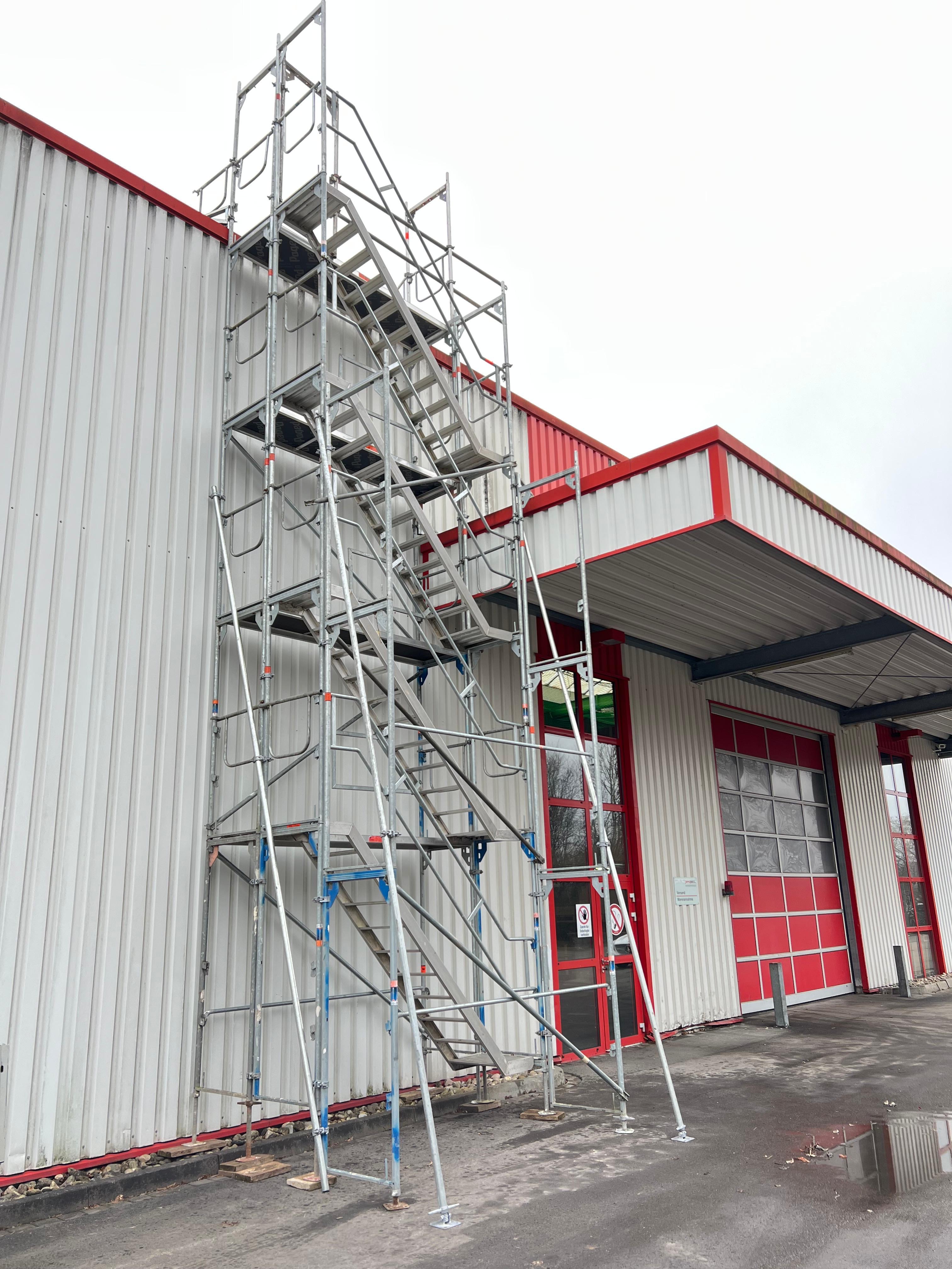 Treppenturm mit Treppenaufstieg an einer Industriehalle mit Wellblechfassade